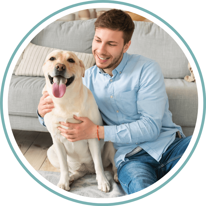 Young happy man cuddling his dog sitting on floor